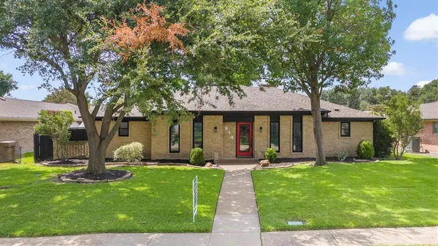 a front view of a house with a yard and tree