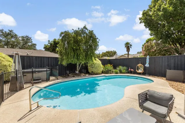 a swimming pool with outdoor seating and wooden fence