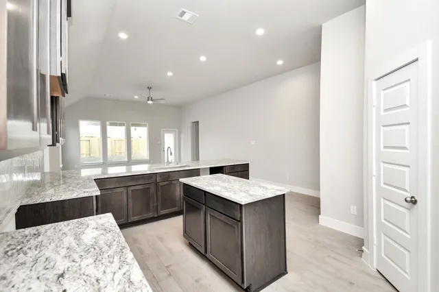 a large kitchen with stainless steel appliances kitchen island granite countertop a sink and cabinets