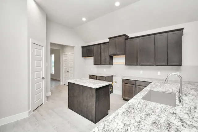 a kitchen with stainless steel appliances kitchen island granite countertop a sink stove and refrigerator
