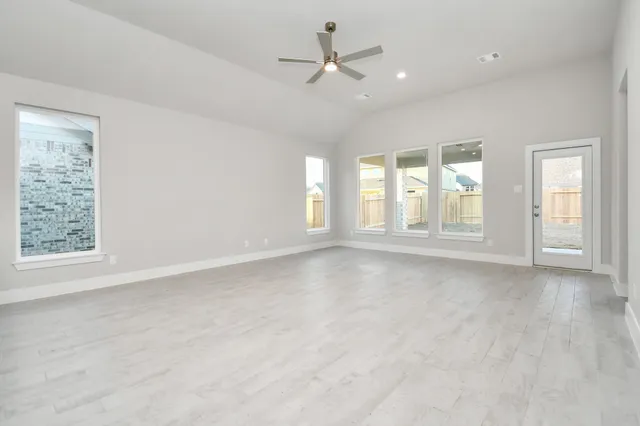 an empty room with chandelier fan and windows