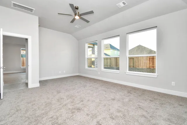 an empty room with chandelier fan and windows