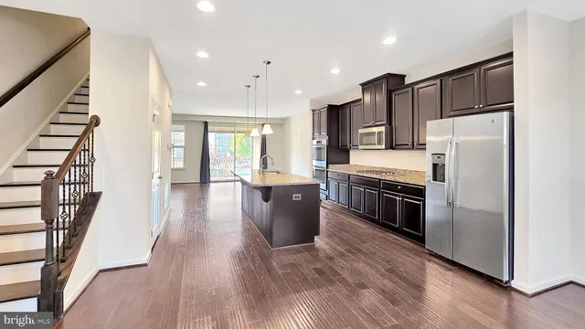 a kitchen with kitchen island wooden floors appliances and cabinets