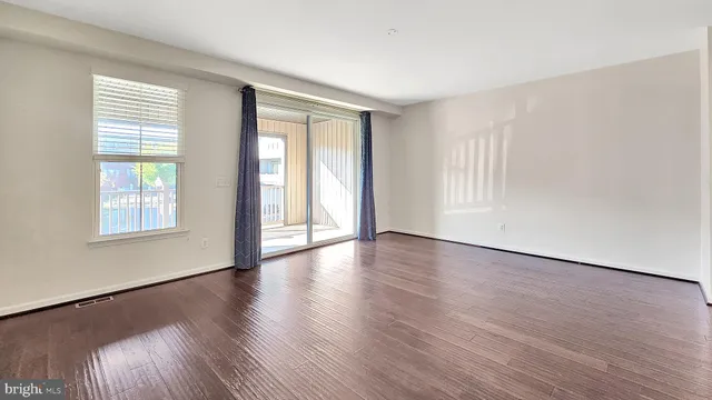 an empty room with wooden floor and windows with curtains view