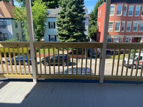 a view of a brick house with large trees and stairs