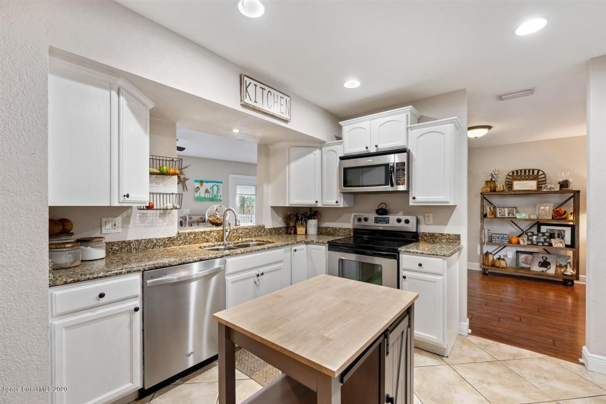 108 Neptune Court Indialantic, FL 32903 - Photo 18 of 33 a kitchen with stainless steel appliances granite countertop a stove top oven a sink dishwasher and a refrigerator with wooden floor