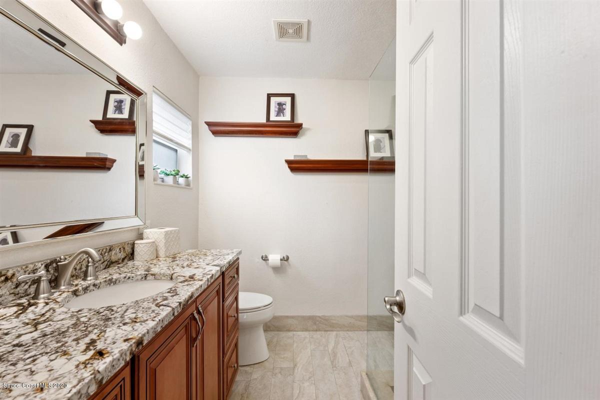 108 Neptune Court Indialantic, FL 32903 - Photo 25 of 33 a bathroom with a granite countertop sink a toilet and a shower