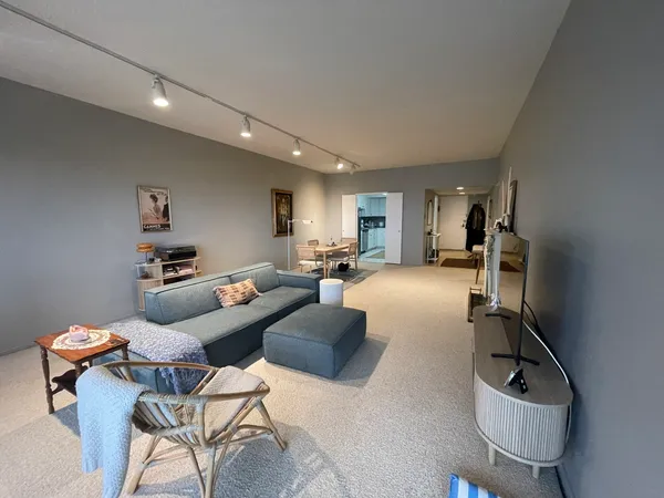a living room with furniture a flat screen tv and a refrigerator