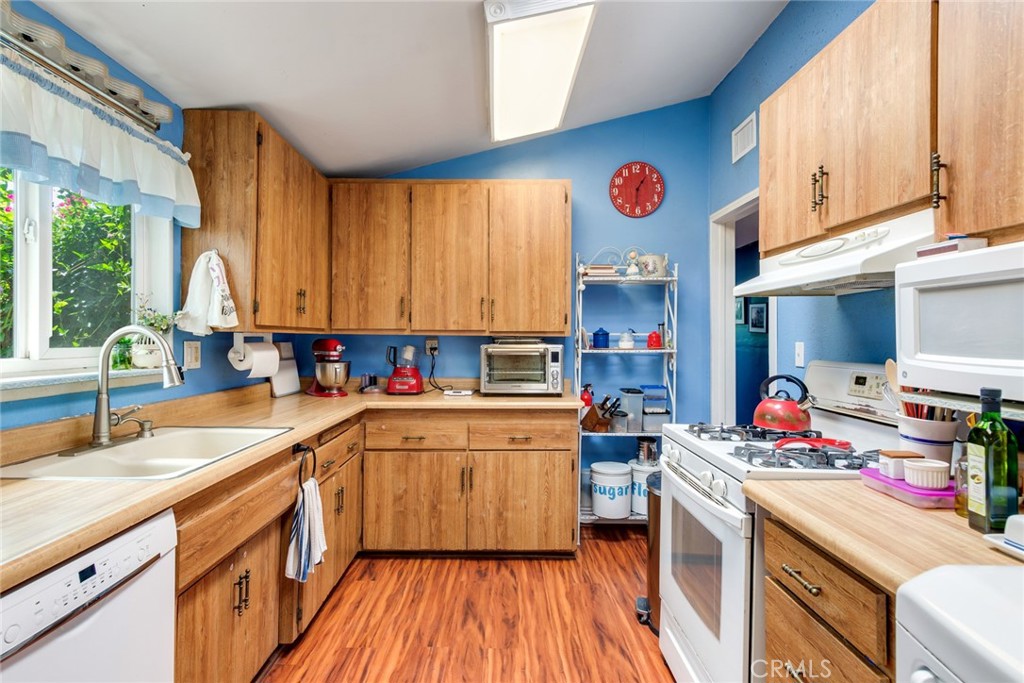 9579 Hampshire Street Rancho Cucamonga, CA 91730 - Photo 13 of 25 a kitchen with a sink dishwasher stove and white cabinets with wooden floor