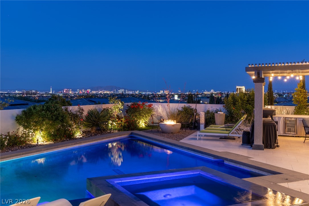10118 Copper Edge Road Las Vegas, NV 89148 - Photo 33 of 48 An illuminated pool and spa at dusk with a dazzling cityscape view.