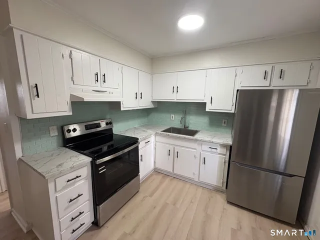 a kitchen with granite countertop white cabinets and stainless steel appliances