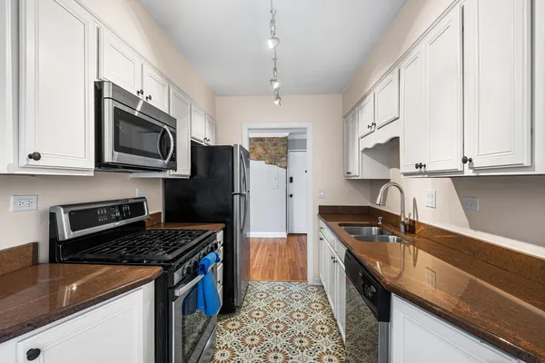 a kitchen with granite countertop a sink a stove oven a refrigerator cabinets and wooden floor