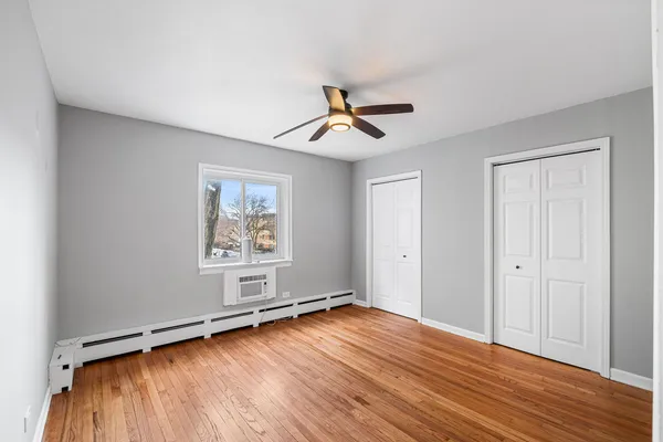 a view of an empty room with window and wooden floor