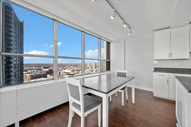 a kitchen with a stove a sink and white cabinets with wooden floor next to windows