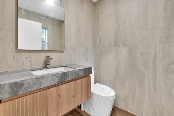 a bathroom with a granite countertop sink and a toilet