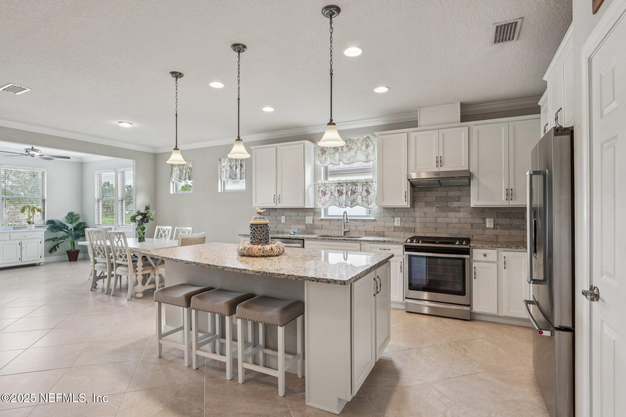 112 Bridge Oak Lane St. Augustine, FL 32095 - Photo 16 of 47 a large kitchen with kitchen island a sink a stove a center island a dining table and chairs