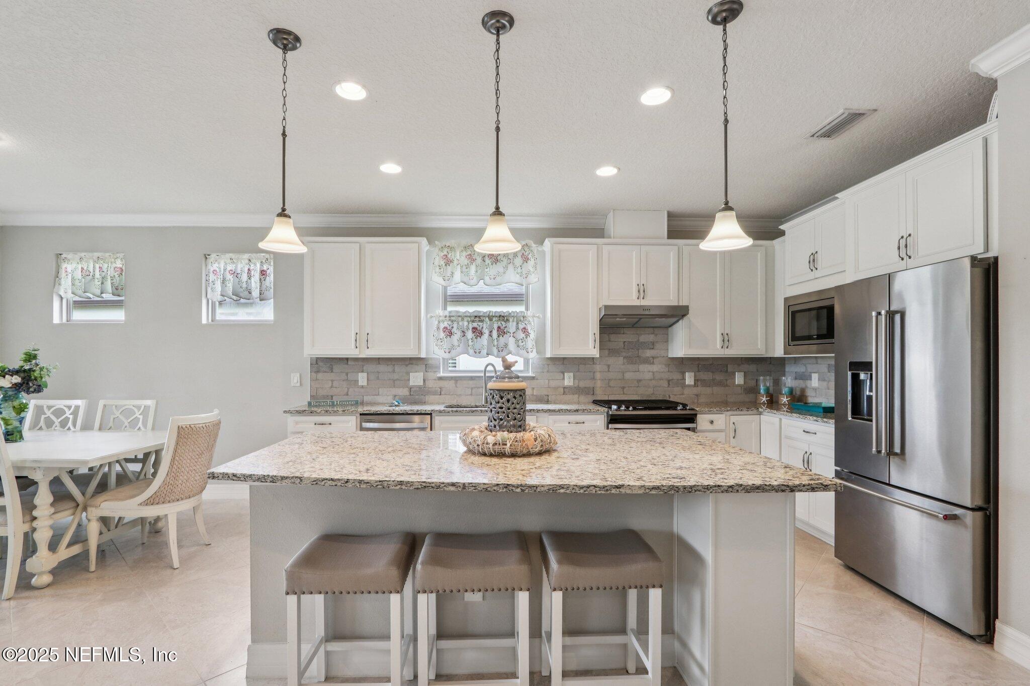 112 Bridge Oak Lane St. Augustine, FL 32095 - Photo 17 of 47 a kitchen with stainless steel appliances granite countertop a stove a refrigerator a kitchen island a sink refrigerator and chairs