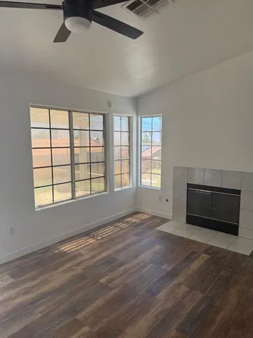 a view of an empty room with a window and wooden floor