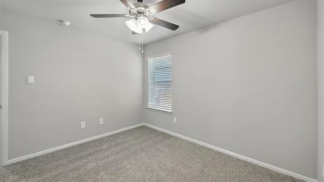 an empty room with a window and a fan