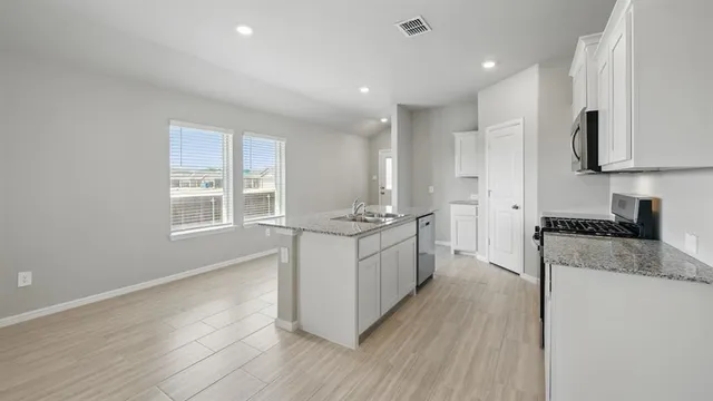 a kitchen with granite countertop a refrigerator stove top oven and sink