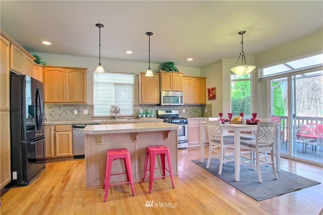 3827 160th Place Southeast Bothell, WA 98012 - Photo 12 of 40 a open kitchen with stainless steel appliances granite countertop a stove a refrigerator a kitchen island a dining table and chairs