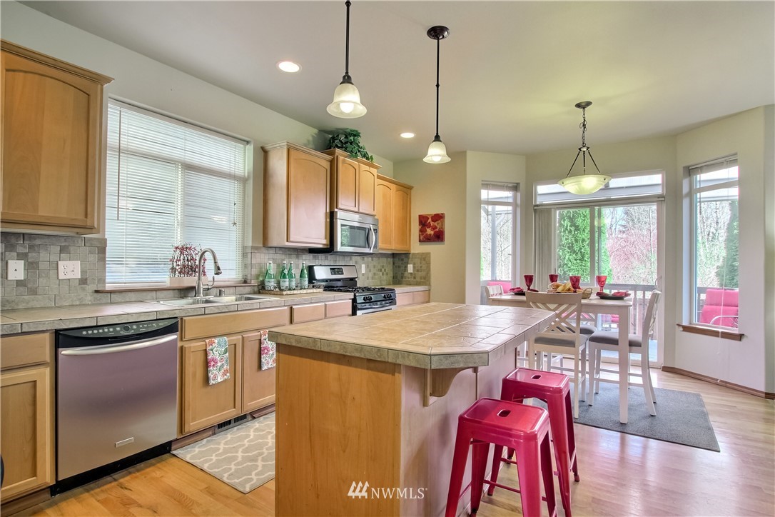 3827 160th Place Southeast Bothell, WA 98012 - Photo 14 of 40 a kitchen with stainless steel appliances kitchen island granite countertop a stove a sink a refrigerator white cabinets and wooden floor