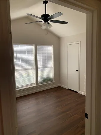 a view of an empty room with wooden floor and a window