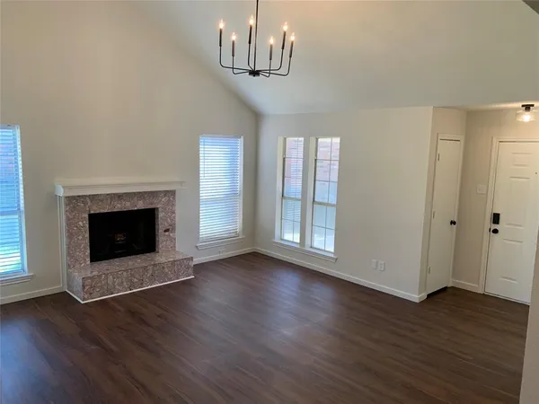 a view of an empty room with wooden floor fireplace and a window