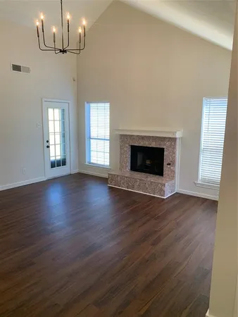 a view of an empty room with wooden floor fireplace and a window