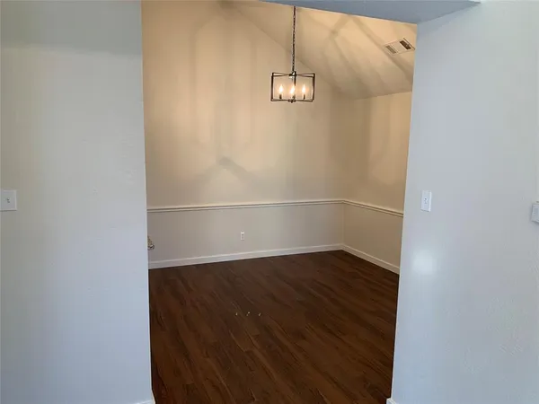an empty room with wooden floor and chandelier