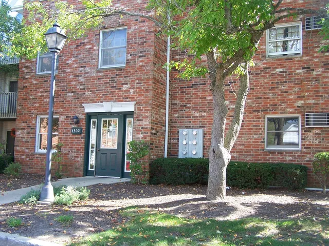 a view of a brick house with a yard and large tree