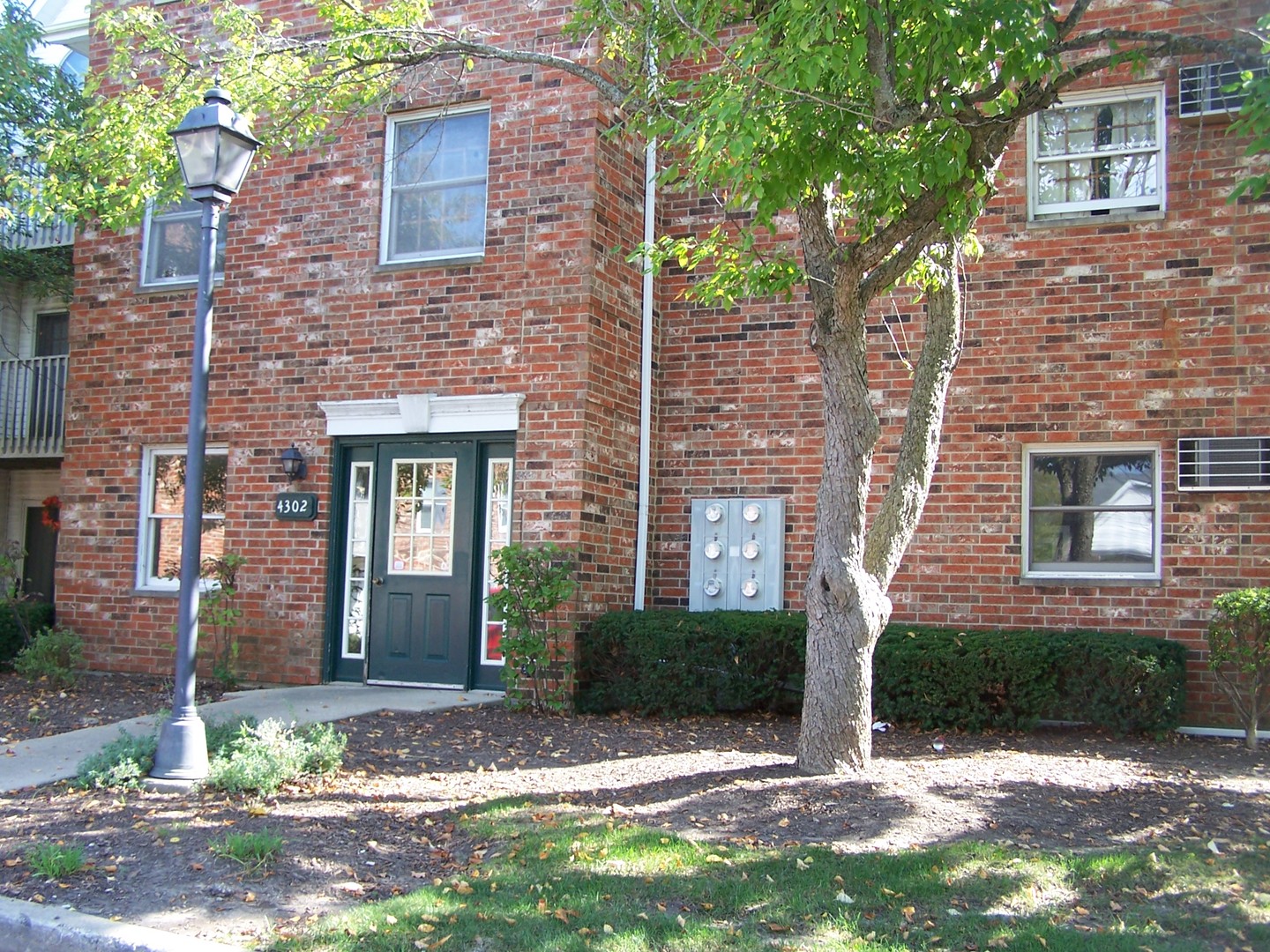 a view of a brick house with a yard and large tree