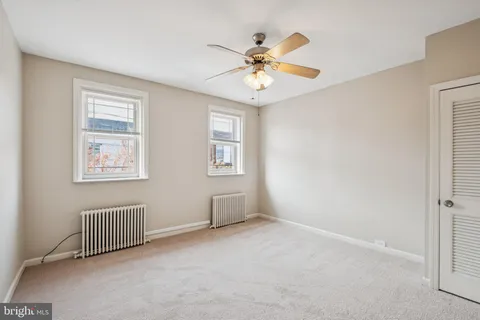 an empty room with windows and fan