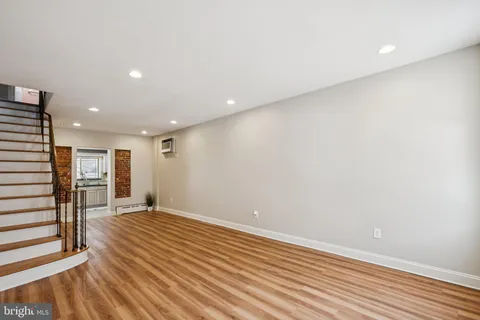 a view of an empty room with wooden floor and stairs