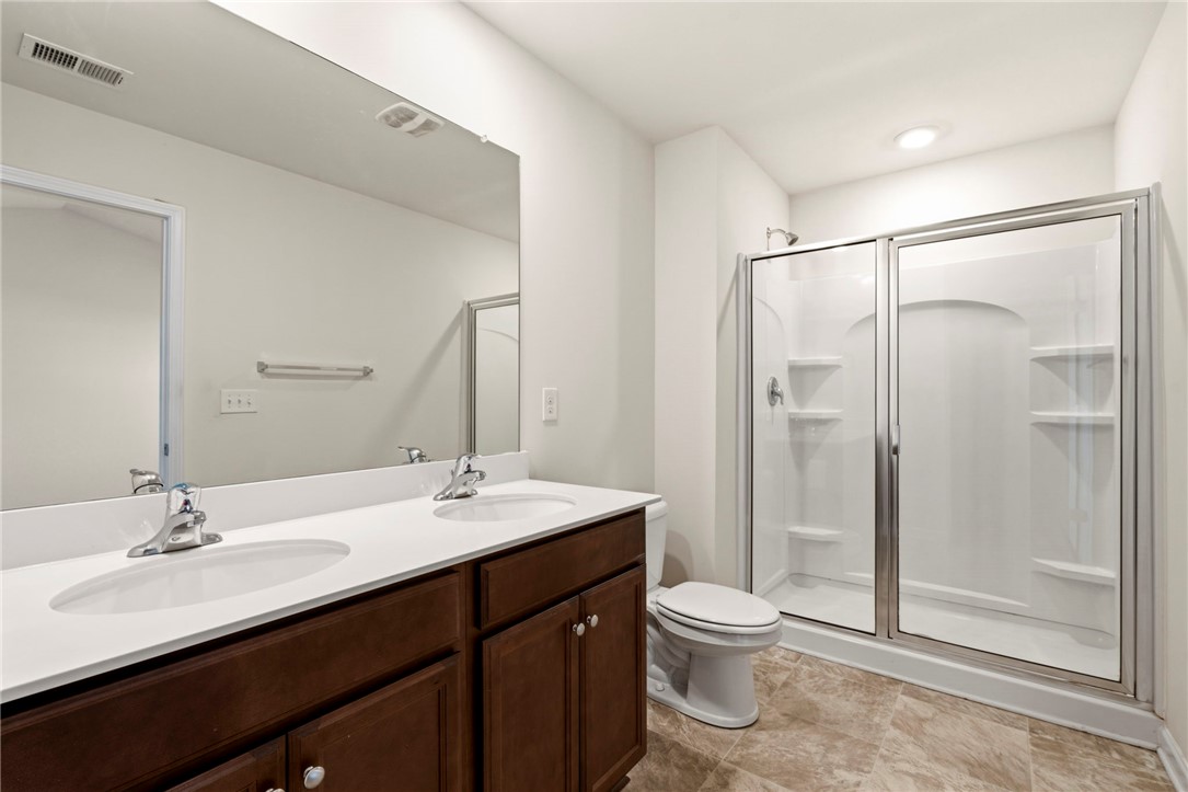 205 Hillendale Way Pelzer, SC 29669 - Photo 17 of 29 This bathroom features a double vanity and a glass-enclosed shower, offering practical elegance.