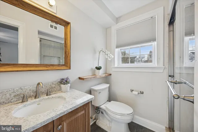 a bathroom with a granite countertop toilet sink and mirror