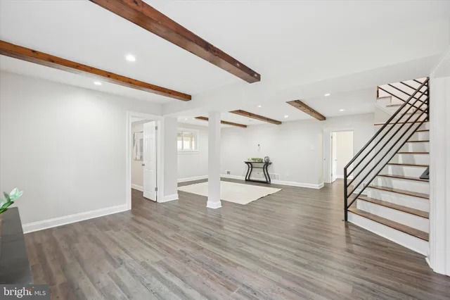 a view of an empty room with wooden floor and stairs