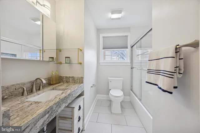 a bathroom with a granite countertop sink a toilet and a mirror