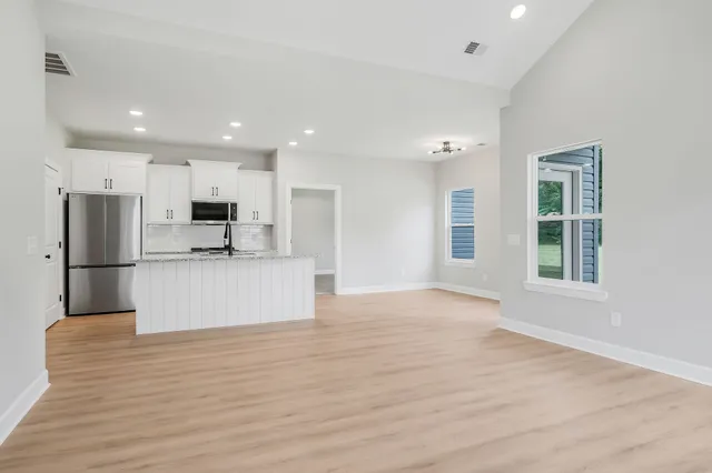 a view of kitchen with kitchen island a sink wooden floor and stainless steel appliances