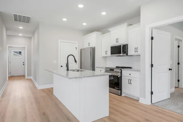 a kitchen with stainless steel appliances granite countertop a stove top oven a refrigerator a sink and a oven with wooden floors