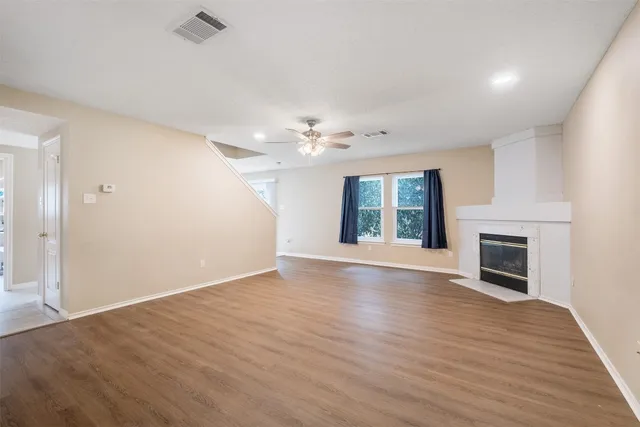 an empty room with wooden floor fireplace and window
