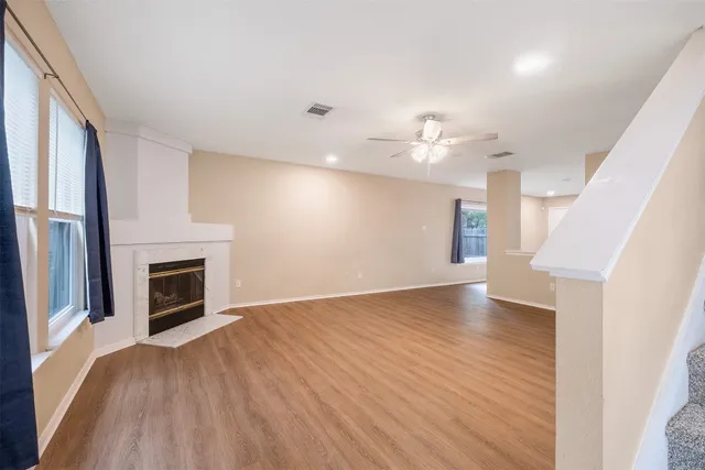 an empty room with wooden floor fireplace and windows