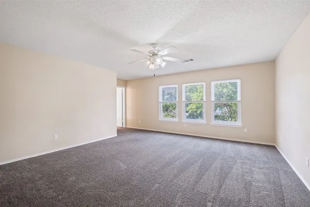 an empty room with windows and chandelier fan
