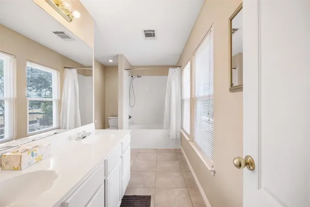 a spacious bathroom with a tub shower and a sink
