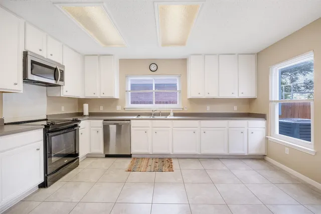 a kitchen with granite countertop a stove top oven microwave and cabinets