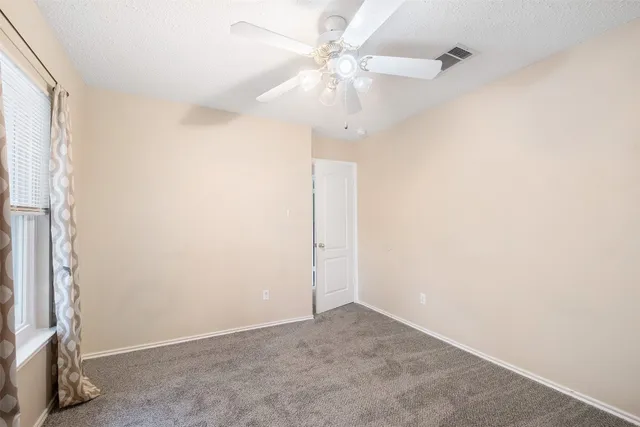 an empty room with a chandelier fan and windows