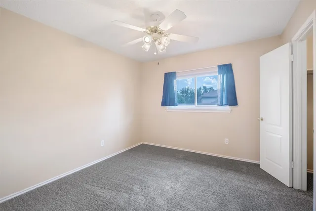 an empty room with a window and a ceiling fan