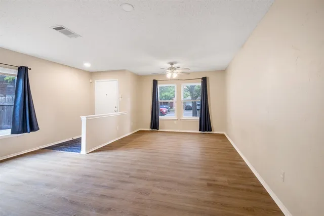 a view of an empty room with a window and wooden floor