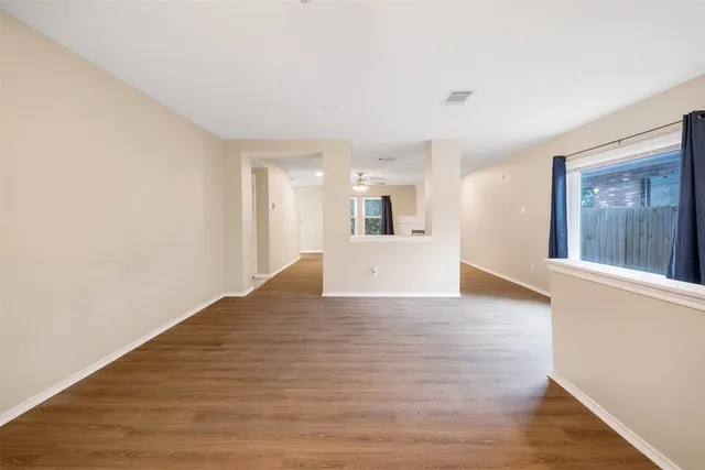 a view of an empty room with wooden floor and a window