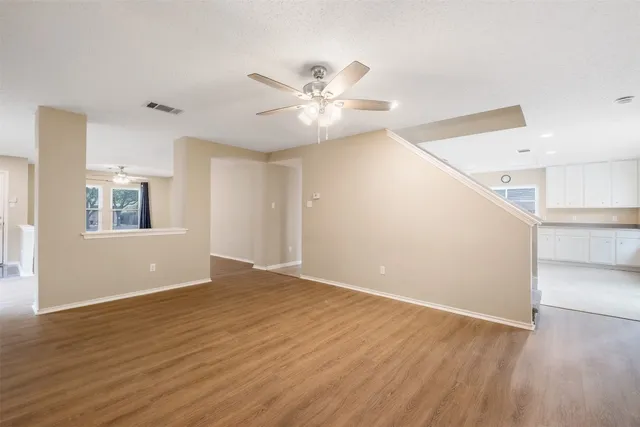 a view of an empty room with window and wooden floor